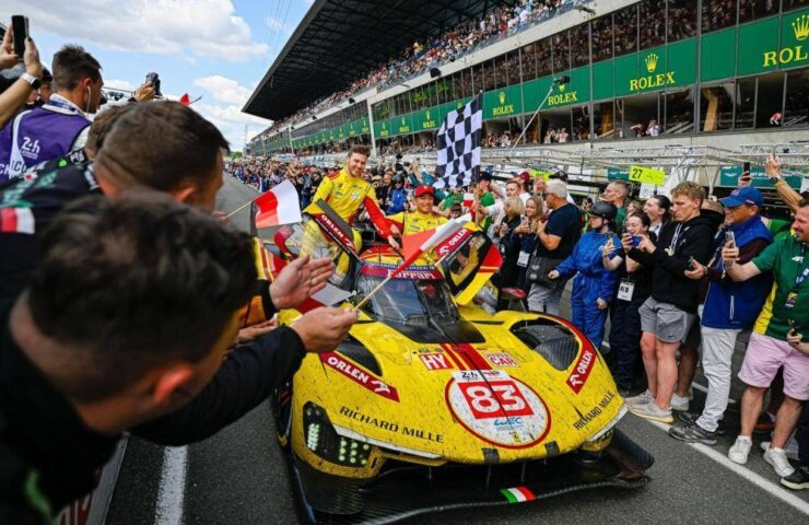 The AF Corse team and drivers celebrate their historic 2025 Le Mans victory with the #83 Ferrari 499P, surrounded by fans and a checkered flag.