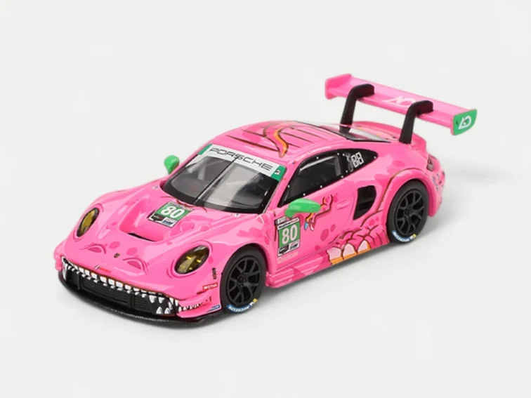 A front three-quarters view of the MINI GT 1/64 "Roxy" the T-Rex Porsche 911 GT3 R, showing the detailed dinosaur teeth on the front splitter and eye livery on the headlight.