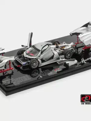 An "exploded" view of the full open 1:43 Pagani model, the Huayra R, showing the main chassis and all of its removable silver and carbon fiber body panels on stands.