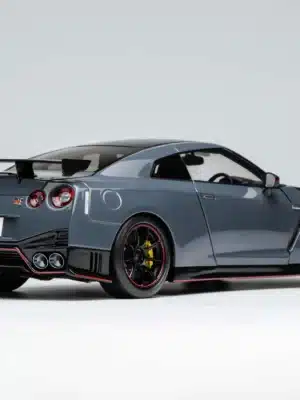 The iconic rear three-quarter view of the Motorhelix GT-R NISMO in 1:18 scale, highlighting the signature quad taillights and carbon fiber GT wing in Stealth Gray.